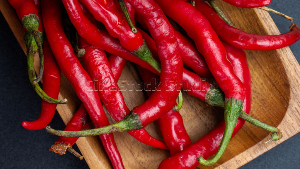 Organic red chili peppers displayed on a rustic wooden background