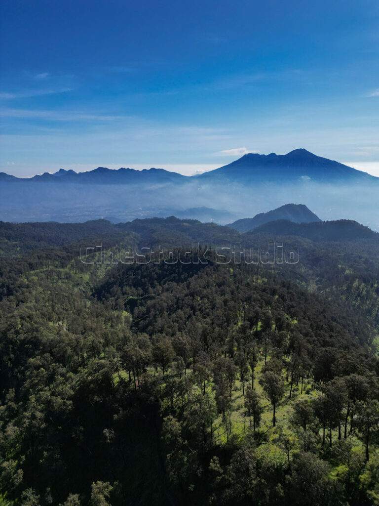 Aerial view of Arjuno Welirang Mountains with blue sky and thin mist in the morning.