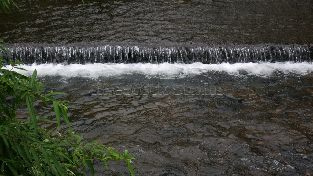 Clear stream of the mini waterfall with white foam.