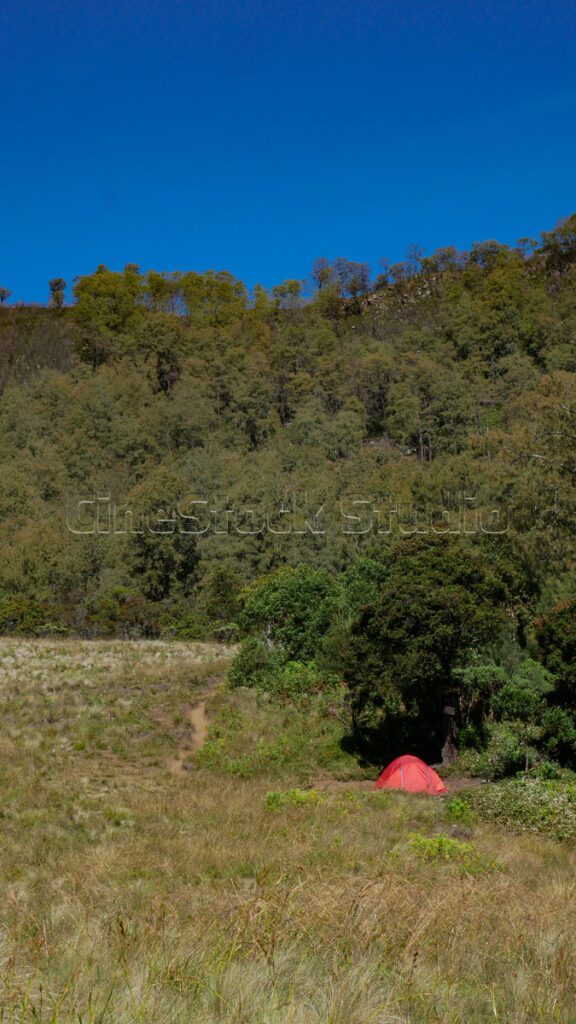 Red tent with Mount Butak peak in the background.
