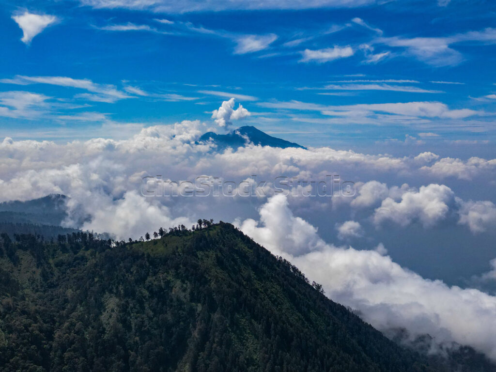 Mount Semeru is seen towering among the dramatic sea of clouds and blue sky.