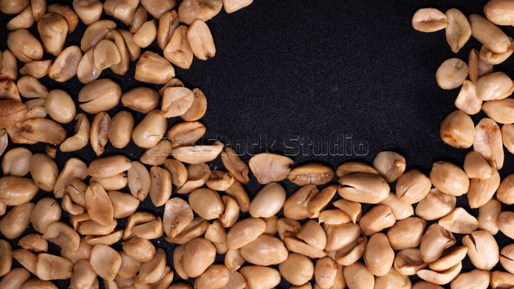 Artistic arrangement of roasted peanuts in circular shape.