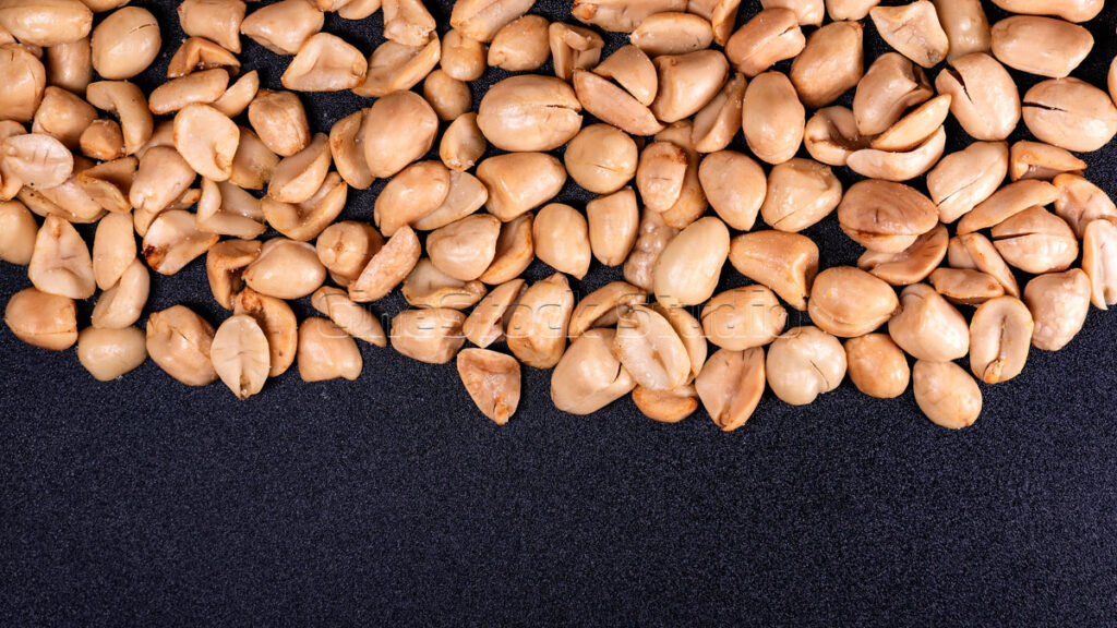 Top view Roasted Shelled Peanuts on Textured Dark Surface.