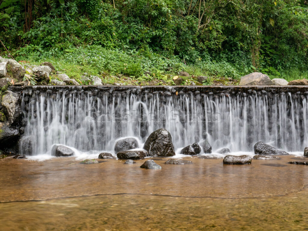 Serene tropical waterfall in a mountain botanical garden with smooth flow effect from long exposure.