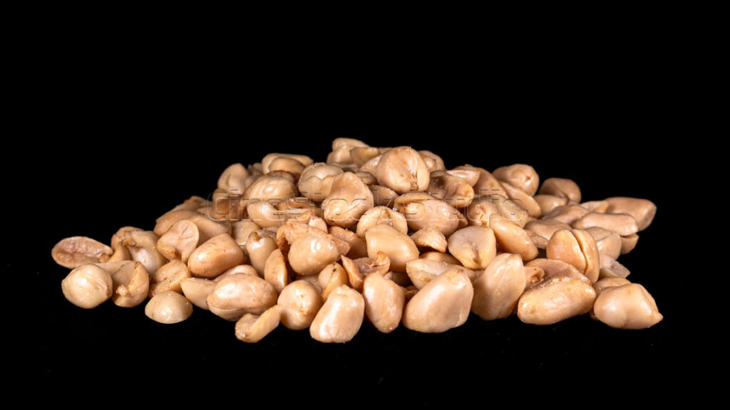 Pile of roasted peeled peanuts on black background.