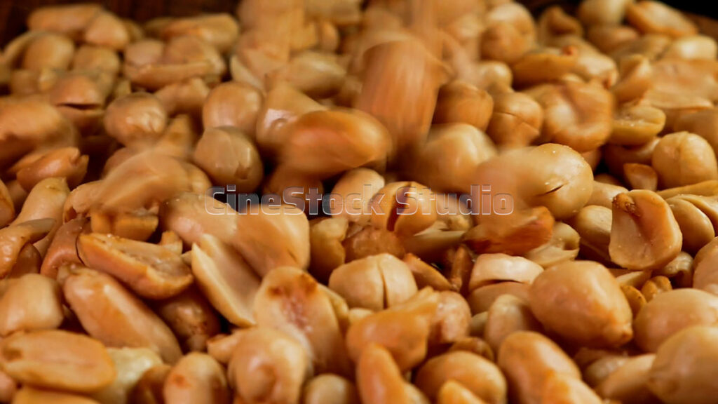 Cinematic rotation of golden roasted peanuts spinning on a professional turntable.