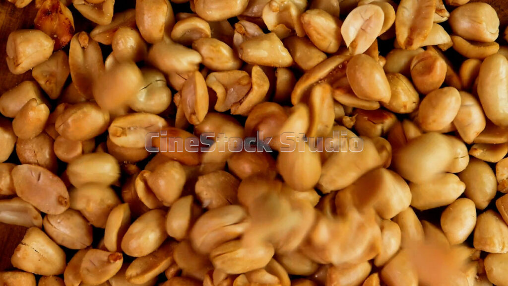 Close-up of fried garlic peanuts on a wooden plate rotating 360 degrees.