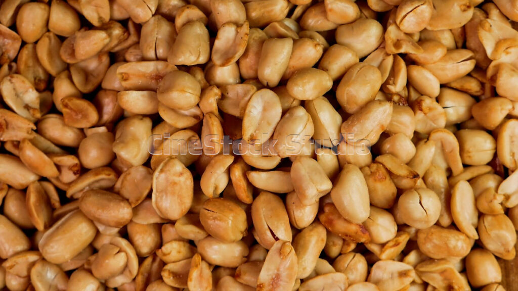 Top view of crispy fried garlic peanuts rotating 360 degrees on a black background.