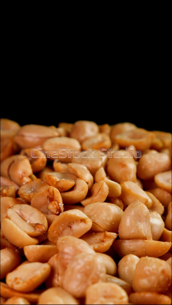 Vertical 360-degree spin of a pile of fried peanuts with sharp lighting on dark background.