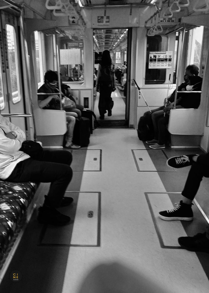 The interior of a moving commuter line train with passengers sitting on the benches.