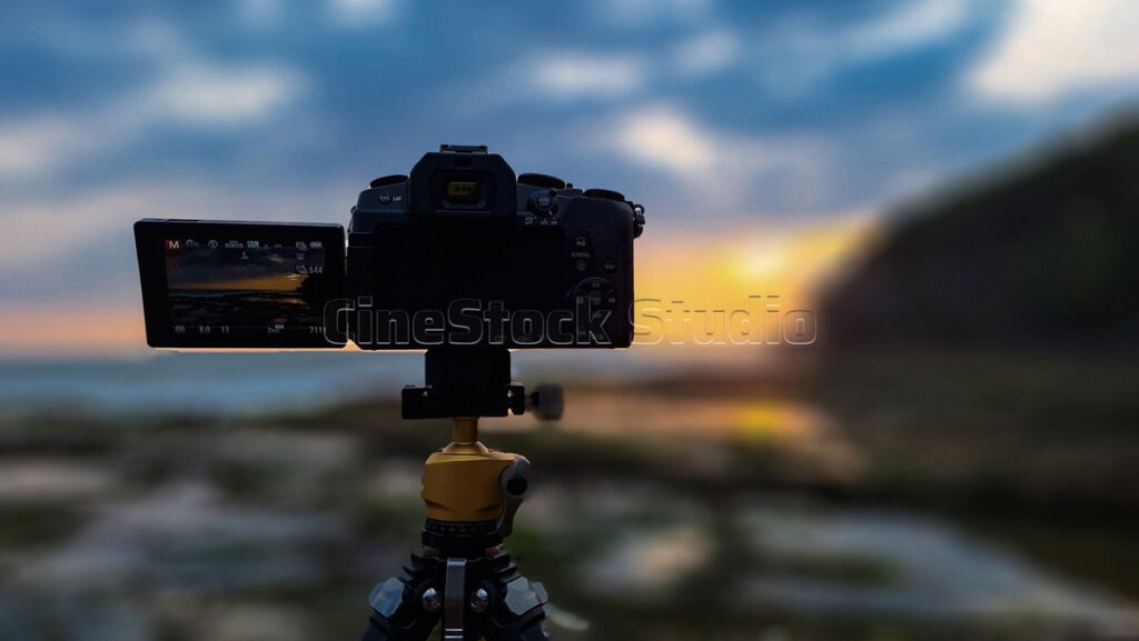 A close-up back view of the Lumix G85 camera screen with a soft-focus bokeh background of a golden ocean sunset.
