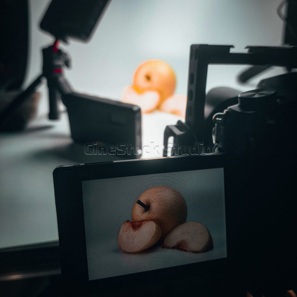 A Lumix G85 camera preview screen focusing on a sliced pear macro setup with studio diffusers in the background.