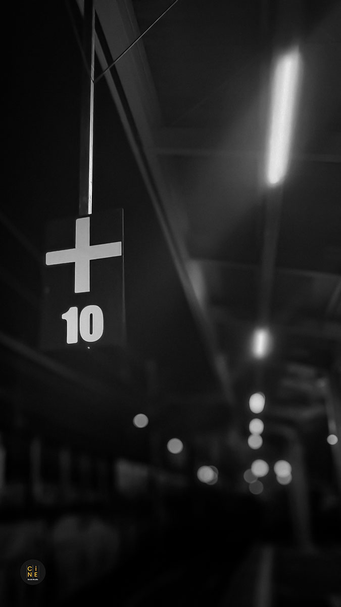 A vertical shot of a railway platform number sign under dim station lights.