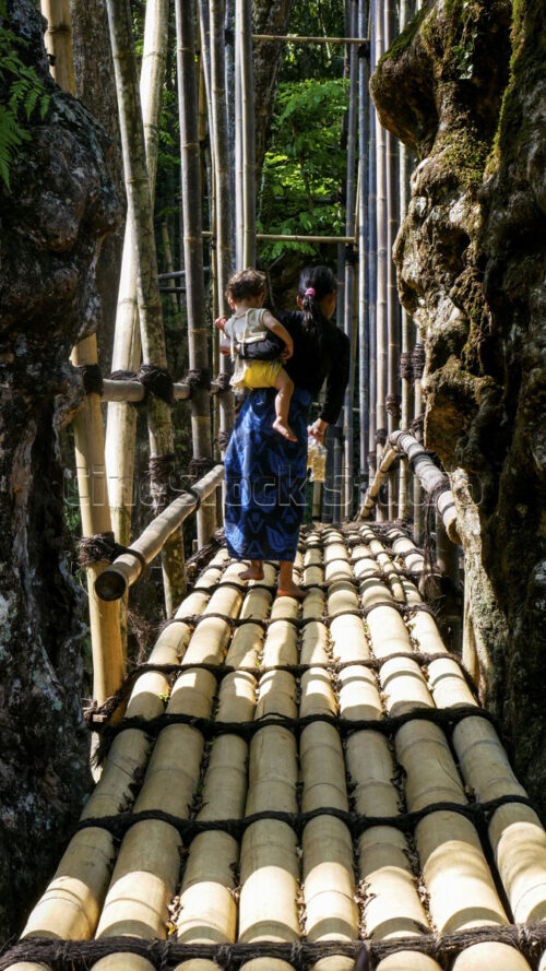 A glimpse of daily life: a Baduy woman safely crossing the Gajeboh Bamboo Bridge while carrying her child on her back. A Baduy mother carrying her child while walking across the bamboo bridge.