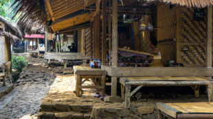 A quiet morning scene on a traditional Baduy house porch used for daily weaving activities. Authentic Baduy wooden stilt house terrace with weaving tools