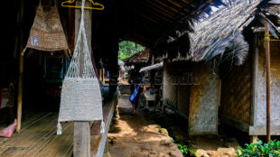 Exploring the serene atmosphere of Kanekes village where weaving is part of the daily landscape. A view of a narrow Baduy village path with weaving equipment in sight