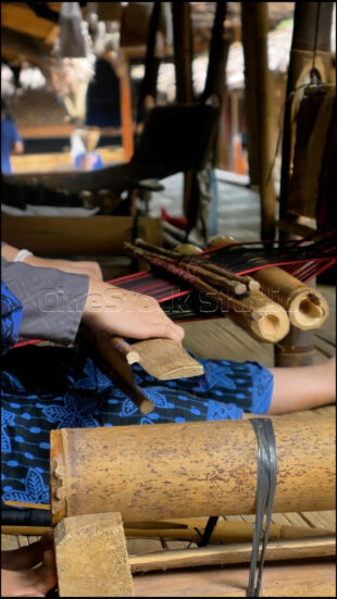 Detailed view of the manual precision required in the traditional Baduy weaving process. Close-up of a Baduy weaver's hands adjusting the bamboo loom