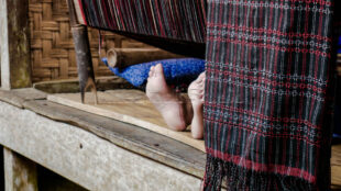 A unique perspective showing the sitting posture and comfort while weaving for hours. Close-up of a weaver's feet tucked under the loom while working