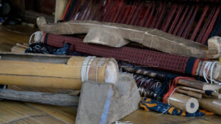 A look at the raw materials and manual tools used by Baduy women in their craft. Traditional weaving tools and half-finished fabric stored indoors