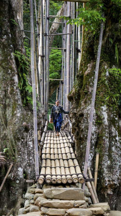 Traditional transit: a local women approaches the iconic Gajeboh Bamboo Bridge, a vital path for those traveling between the territories. A Baduy women walking toward the stone stairs of the Gajeboh bridge entrance.