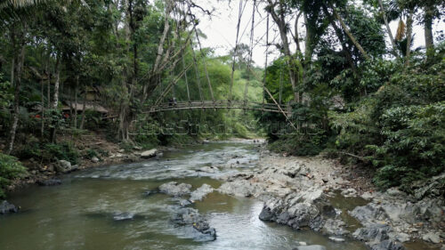 A serene landscape view of the Ciujung River, showing the natural environment surrounding the Gajeboh area. Wide landscape of Ciujung River with the bamboo bridge in the distance.