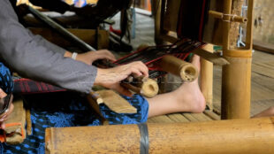 Capturing the intricate wooden and bamboo structure of the "Gedogan" weaving tool. Macro shot of the bamboo and thread mechanism of a Baduy loom